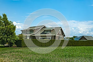 Farm country house in green field. Countryside of Canada. Rural Farmhouse with barns on a sunny day in a summer