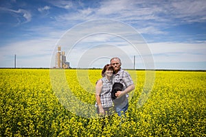 Farm couple standing in a canola field in an embrace