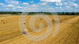 A farm field after harvest with haystacks on a sunny august day