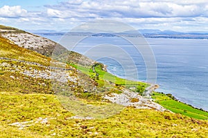 Farm field with stone wall in Burren way trail with Galway bay i