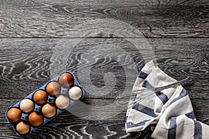 Farm fresh organic large brown and white eggs in carton on rustic dark oak wood background table.