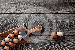 Farm fresh organic large brown and white eggs in carton on rustic dark oak wood background table.