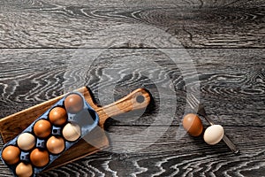 Farm fresh organic large brown and white eggs in carton on rustic dark oak wood background table.