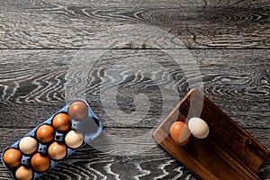 Farm fresh organic large brown and white eggs in carton on rustic dark oak wood background table.