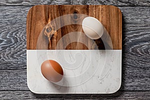 Farm fresh organic large brown and white eggs in carton on rustic dark oak wood background table.