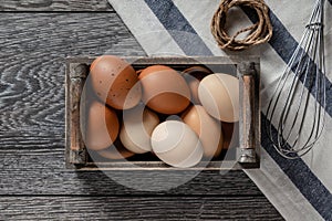 Farm fresh organic large brown and white eggs in crate on rustic dark oak wood background table.