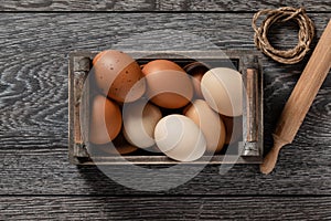 Farm fresh organic large brown and white eggs in crate on rustic dark oak wood background table.