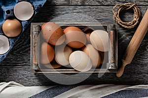 Farm fresh organic large brown and white eggs in crate  on rustic dark oak wood background table.