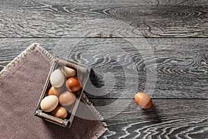 Farm fresh organic large brown and white eggs in egg wooden crate on rustic dark oak wood background table.
