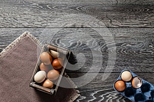Farm fresh organic large brown and white eggs in wooden crate on rustic dark oak wood background table.