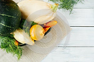 Farm fresh vegetables: zucchini, carrots, onions, pumpkin, dill and parsley on a light wooden table, top view