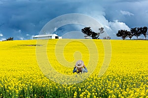 Farm girl in field of canola with storm looming