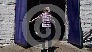 Farm girl opens the gate to the barn