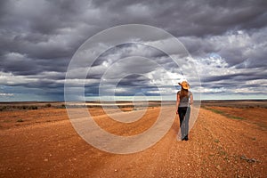 Farm girl watching storm over the arid desert