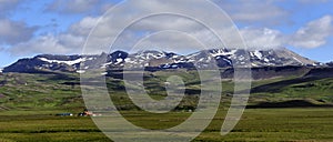 Farm house below the high Icelandic mountains