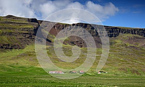 A farm in Iceland at the foot of a mountain range