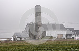 A farm with a large silo and a house in the background