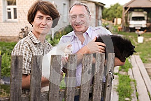 Farm neighbors with cats in their arms talking