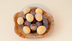 Farm organic plums and yellow apricots. Handmade teak bowl