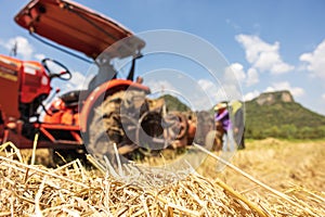 On a farm in Ratchaburi, Thailand, farmers use agricultural machine to compress and bundle rice straw