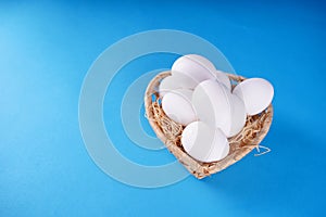 Farm raw, fresh white chicken egg in a basket on a blue background. Concept: a fresh egg for the morning breakfast