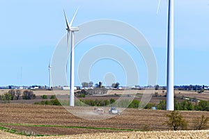 Farm scene with a tractor seeding a farm fields amongst wind towers photo