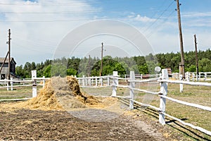 Farm scene with wooden log fence, bale of hay and barn. Countryside rural landscape