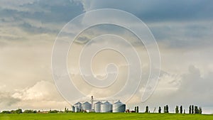 Farm silos at a distant farm at sunset.