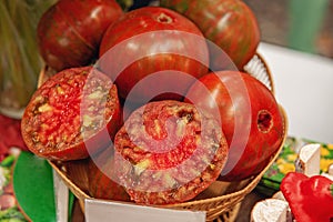 Farm tomatoes in a basket lie in the window of the farmer`s market. The latest hybrid varieties of vegetables. Isolated on black