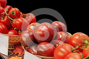 Farm tomatoes in a basket lie in the window of the farmer`s market. The latest hybrid varieties of vegetables. Isolated on black