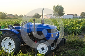 A farm tractor without a driver stands on a farm field at sunset. Subsidizing and supporting farms, modernization of technical