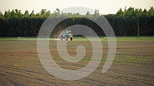 Farm tractor fertilize spray wheat field with sprayer from pesticide herbicide