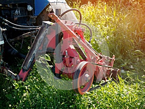 Farm tractor green mowing high grass in a Sunny summer day. Close-up.