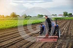 A farm tractor works the soil of an agricultural field. Milling soil, crushing and loosening ground before cutting rows