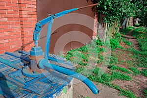 Farm village county water well with hand manual pump. Old utility supply facilities. Country lifestyle image. Primitive mechanism