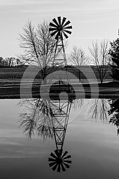 Farm Windmill Silhouette with barren background set against its reflection in a lake II