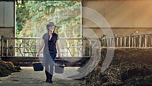 Farm, woman and work with bucket in barn for agriculture, sustainability or maintenance at countryside. Farmer, smile