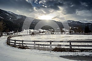 Farm with wooden fence at highland Austrian town at sunset