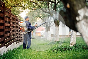 Farm worker spraying pesticide treatment on fruit garden