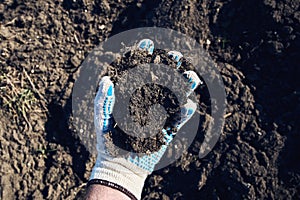 Farmer agronomist holding a clod of earth, closeup of male hand with soil sample from agricultural field photo