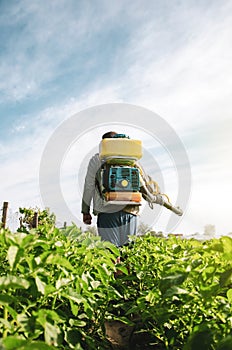 A farmer in an air sprayer cannon sprays a potato plantation. Mist fogger sprayer, fungicide and pesticide. Effective crop