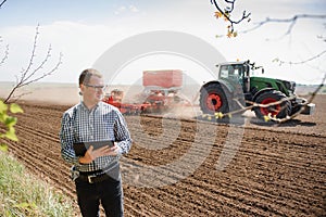 Farmer on background of tractor sowing field. Work in the field. Agriculture concept. Farm work in the field in spring