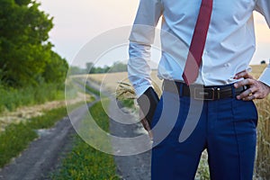 Farmer businessman on a dirt road with a wallet and ears of cereals in his pocket