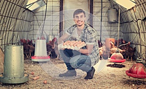 Farmer carrying chicken eggs in coop