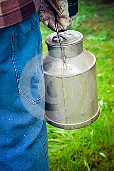 Farmer carrying a vintage dairy milk can.