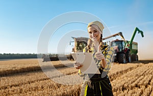 Farmer with clipboard on field keeping track of the grain harvest