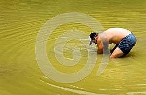 Farmer collecting snails in the pond