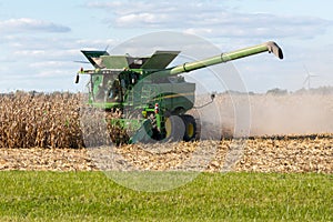 A farmer combining a field of corn in his John Deere combine harvester