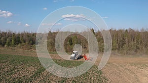A farmer cultivates a field on a crawler tractor and loosens the soil with a disc cultivator against the backdrop of