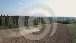 A farmer cultivates a field on a crawler tractor and loosens the soil with a disc cultivator against the backdrop of